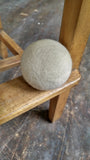 single wool dryer ball displayed on wooden step